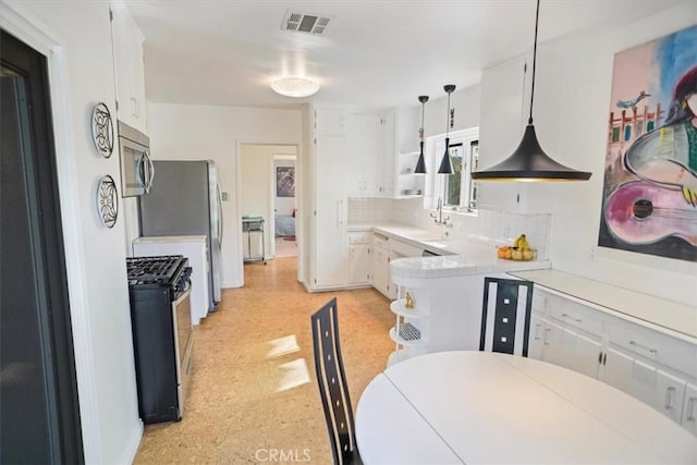 kitchen featuring white cabinetry, kitchen peninsula, stainless steel appliances, decorative backsplash, and pendant lighting