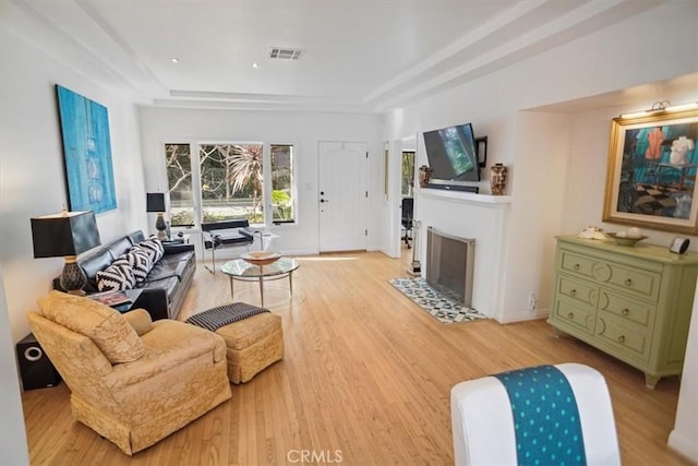 living room with a tray ceiling and light hardwood / wood-style floors