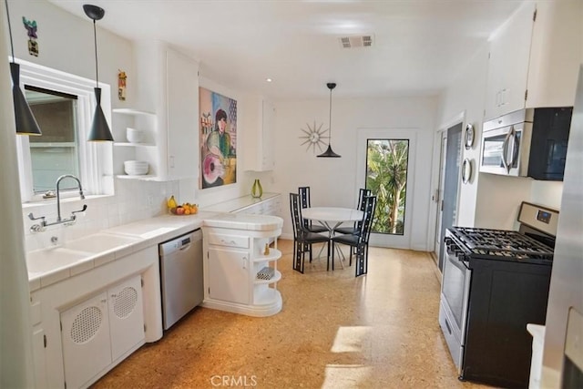 kitchen with hanging light fixtures, appliances with stainless steel finishes, white cabinetry, and tile counters