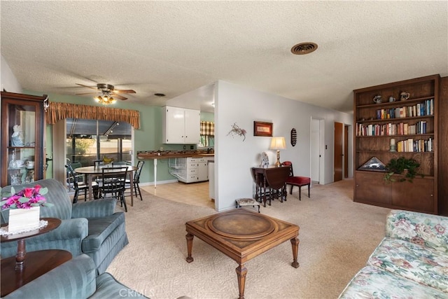 living room featuring ceiling fan, a textured ceiling, and light carpet