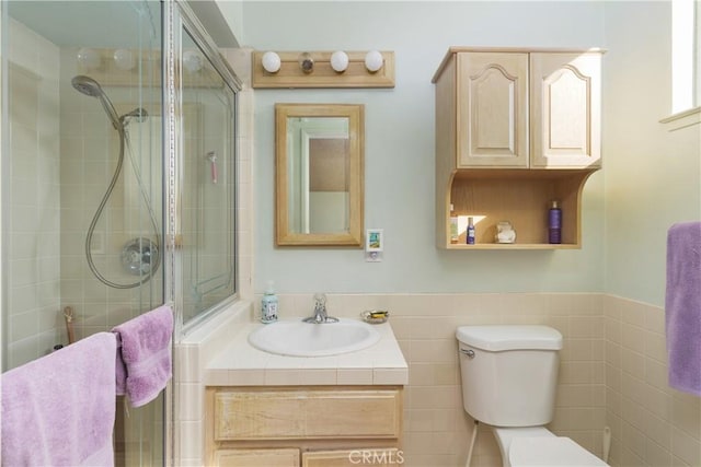 bathroom featuring a shower with door, tile walls, toilet, and vanity