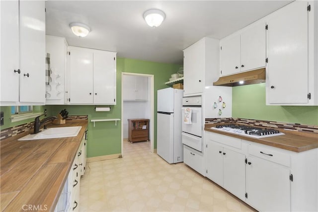 kitchen with butcher block countertops, decorative backsplash, sink, white appliances, and white cabinets