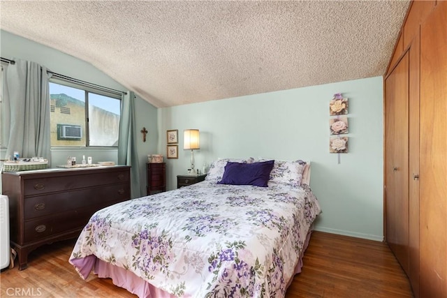 bedroom with a closet, vaulted ceiling, a textured ceiling, and hardwood / wood-style flooring