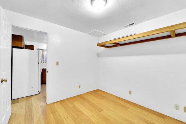 empty room featuring a textured ceiling and light wood-type flooring