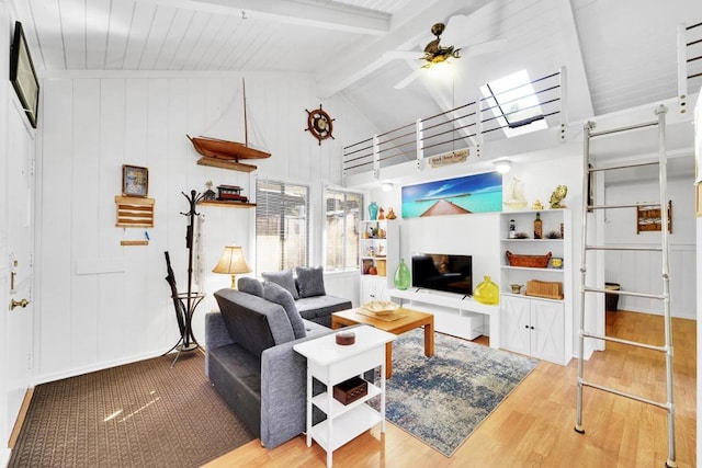 living room with a skylight, high vaulted ceiling, hardwood / wood-style flooring, ceiling fan, and beam ceiling