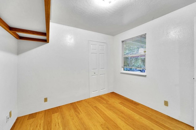 spare room featuring wood-type flooring and a textured ceiling