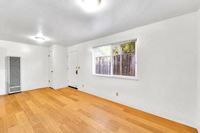 spare room featuring a textured ceiling and light hardwood / wood-style flooring