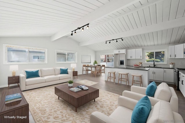 living room with vaulted ceiling with beams, light wood-type flooring, sink, and rail lighting