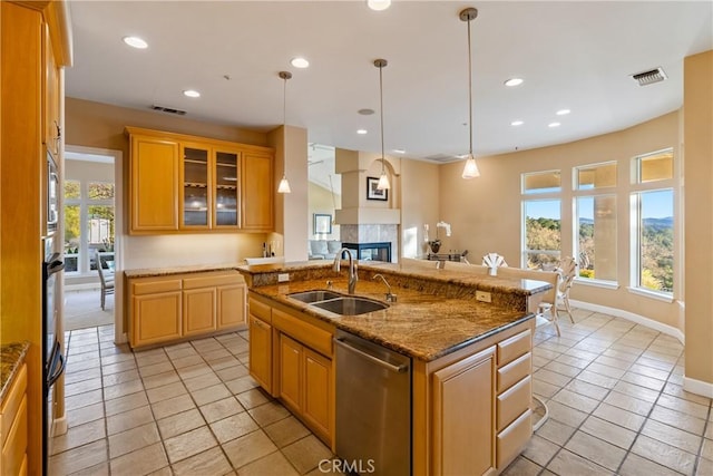 kitchen featuring a sink, visible vents, stainless steel dishwasher, a center island with sink, and glass insert cabinets