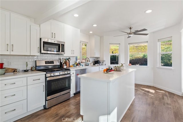 kitchen featuring stainless steel appliances, a center island, light countertops, and white cabinetry