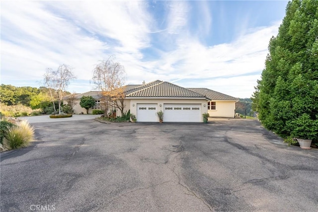 view of front of house with an attached garage, stucco siding, driveway, and a tiled roof