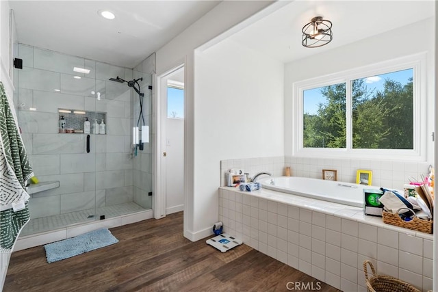 full bath featuring a stall shower, wood finished floors, and a bath