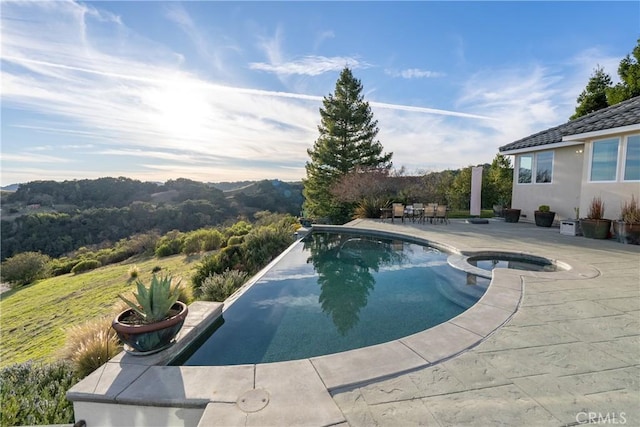 view of pool with a pool with connected hot tub and a patio area