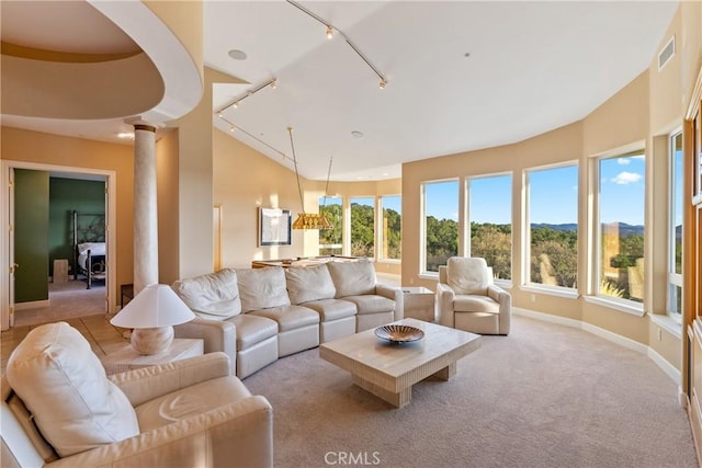 living room featuring vaulted ceiling, plenty of natural light, visible vents, and ornate columns