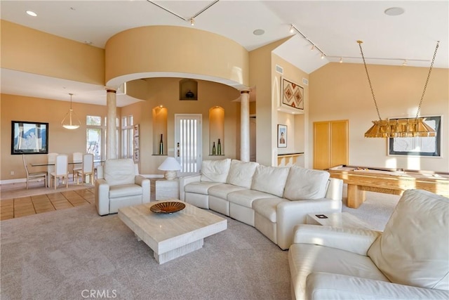 living room with tile patterned floors, carpet, ornate columns, high vaulted ceiling, and track lighting