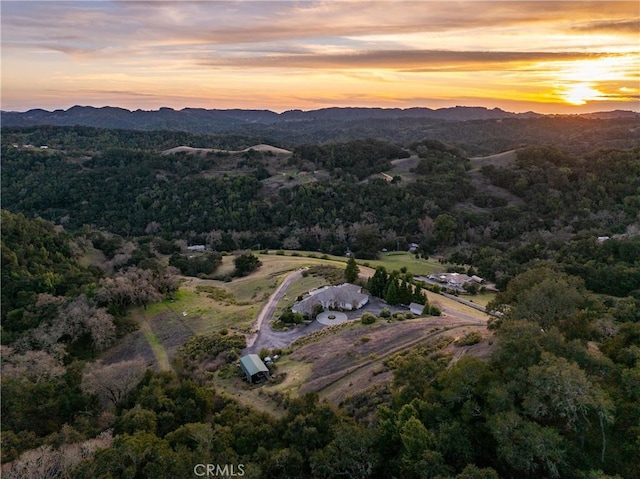 aerial view at dusk with a mountain view and a view of trees