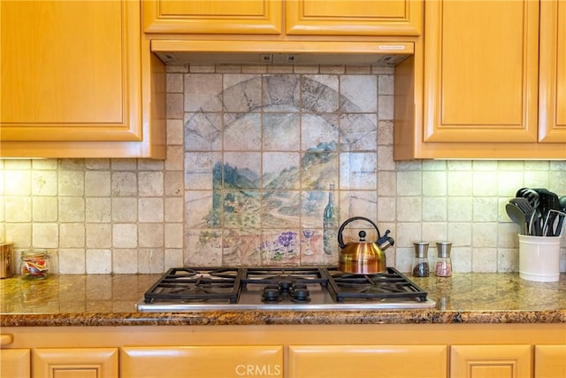 kitchen featuring stainless steel gas cooktop, dark stone counters, and backsplash