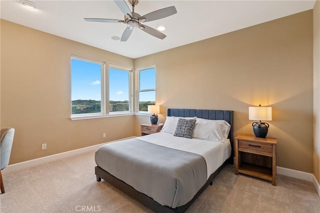 bedroom featuring light carpet, ceiling fan, and baseboards