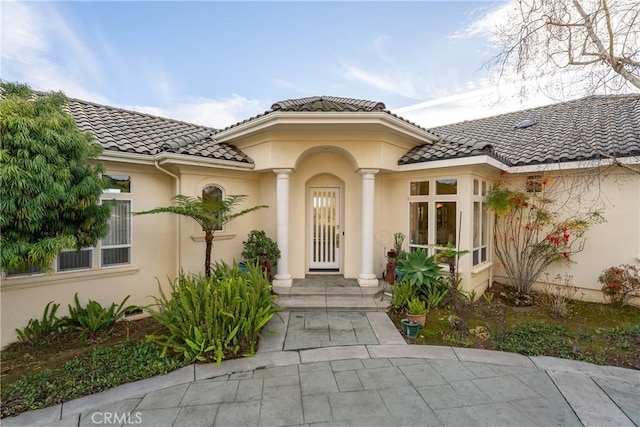 view of exterior entry featuring a tiled roof and stucco siding