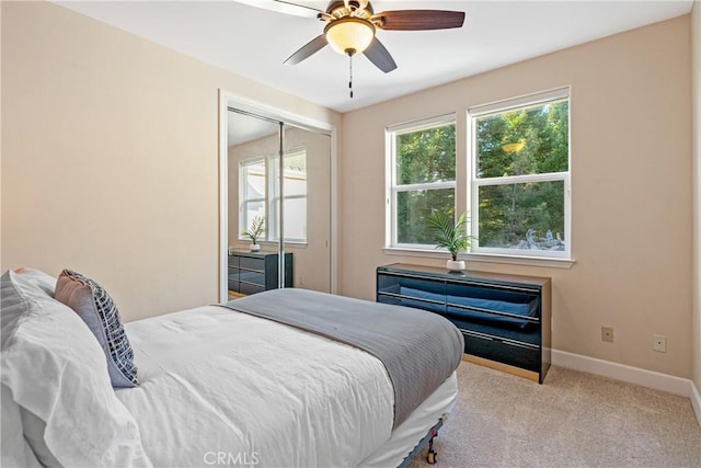 bedroom featuring a ceiling fan, a closet, light colored carpet, and baseboards