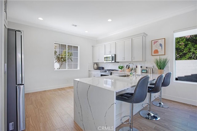 kitchen with white cabinets, stainless steel appliances, sink, kitchen peninsula, and light stone counters