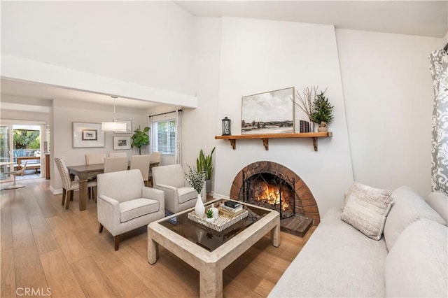 living room featuring light hardwood / wood-style floors, a brick fireplace, and a wealth of natural light