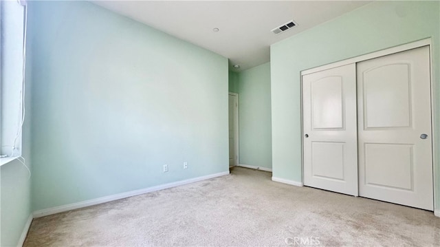 unfurnished bedroom featuring a closet and light carpet