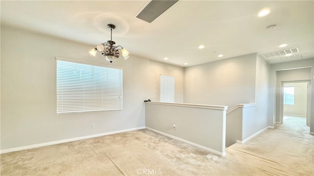 empty room with light carpet and a notable chandelier