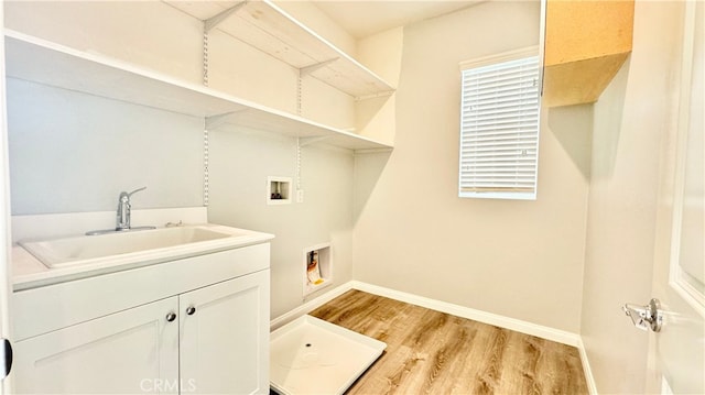 laundry room featuring cabinets, sink, washer hookup, and light hardwood / wood-style floors