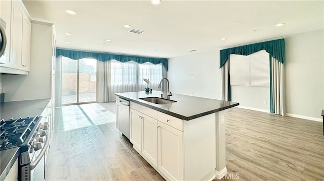 kitchen with white cabinetry, stainless steel appliances, a kitchen island with sink, light wood-type flooring, and sink