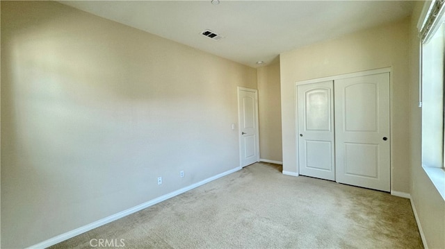 unfurnished bedroom with light colored carpet and a closet