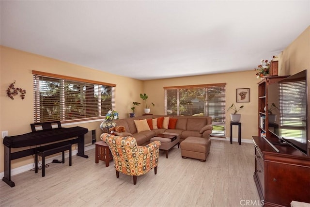 living area with light wood-type flooring, a wealth of natural light, and baseboards