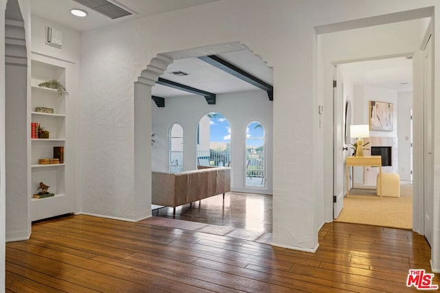 hallway with beam ceiling, built in features, and dark hardwood / wood-style flooring