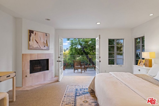 carpeted bedroom with a tile fireplace and access to outside