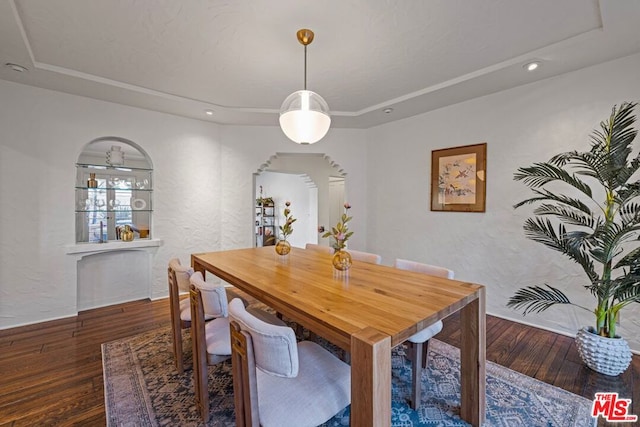 dining area with a raised ceiling and wood-type flooring