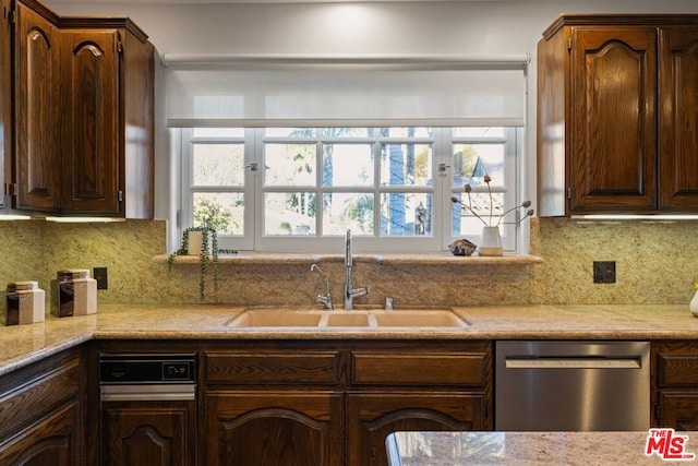 kitchen featuring dark brown cabinets, dishwasher, tasteful backsplash, and sink