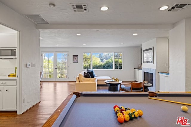 playroom featuring wood-type flooring, pool table, a wealth of natural light, and a tiled fireplace