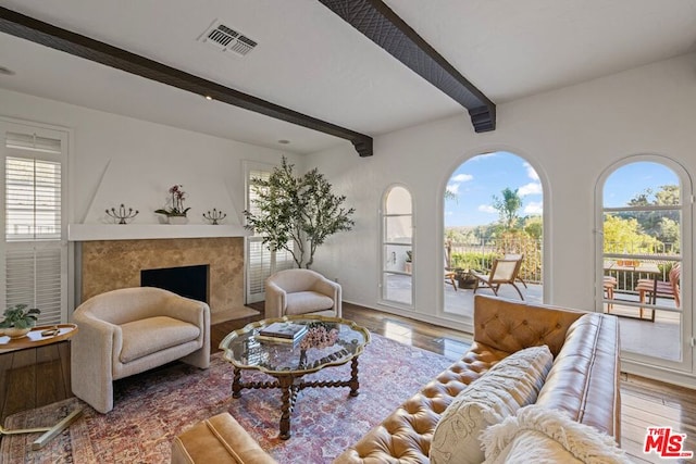 living room featuring hardwood / wood-style flooring, a premium fireplace, and beamed ceiling