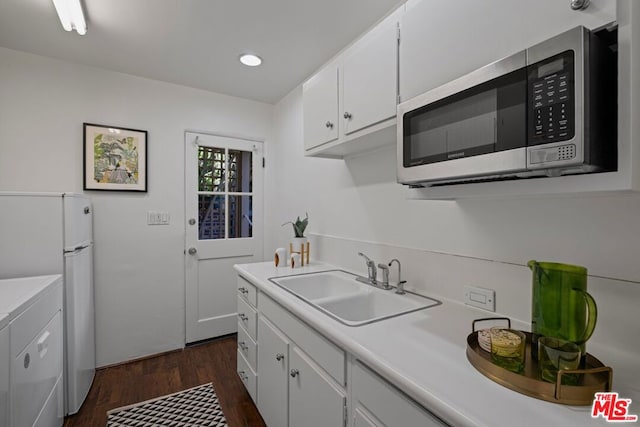 kitchen with white cabinetry, dark hardwood / wood-style floors, washing machine and dryer, white refrigerator, and sink