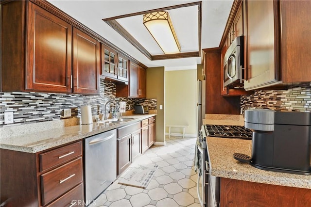 kitchen featuring light stone countertops, sink, decorative backsplash, and stainless steel appliances