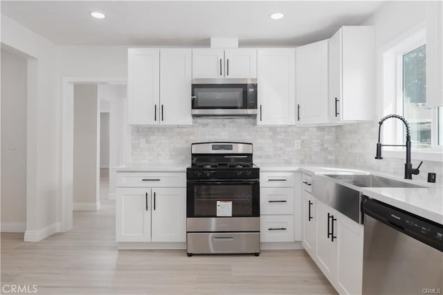 kitchen with appliances with stainless steel finishes, white cabinetry, and tasteful backsplash