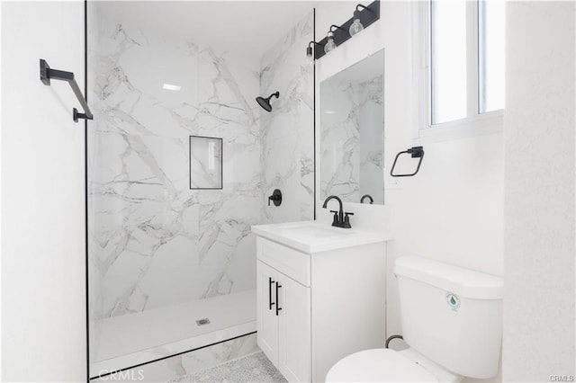 bathroom with toilet, vanity, and a tile shower