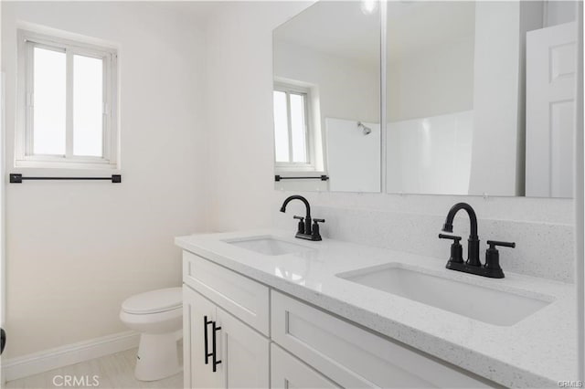 bathroom featuring toilet, vanity, and a healthy amount of sunlight