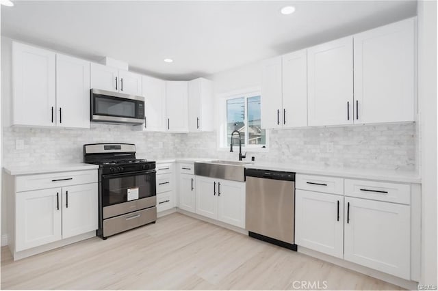 kitchen with tasteful backsplash, white cabinets, sink, and stainless steel appliances