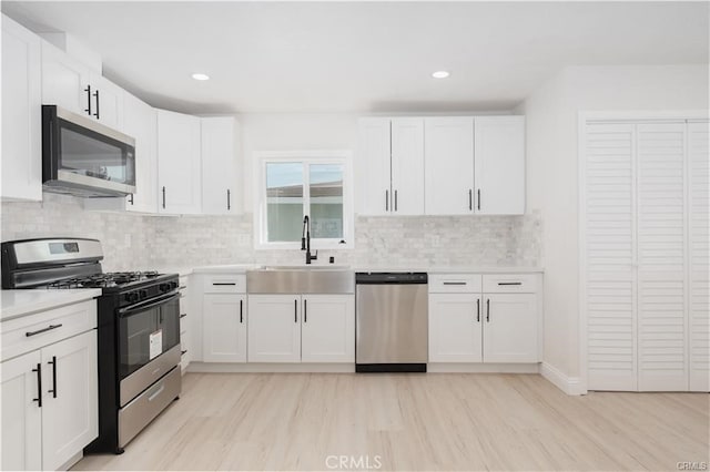 kitchen with appliances with stainless steel finishes, decorative backsplash, white cabinets, and sink