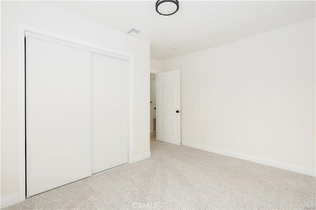 unfurnished bedroom featuring light carpet and a closet