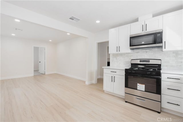 kitchen with light hardwood / wood-style flooring, decorative backsplash, stainless steel appliances, and white cabinetry