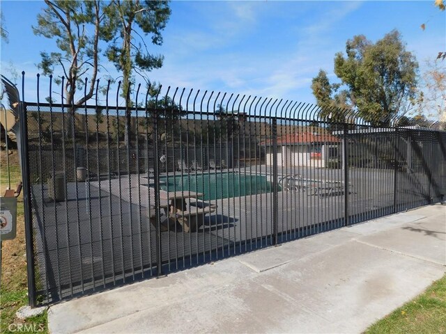 view of gate featuring a patio area and a covered pool