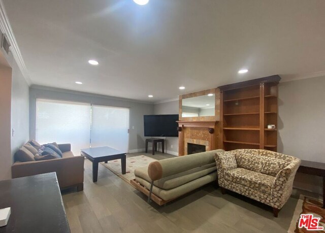 living room with wood-type flooring, a tile fireplace, and ornamental molding