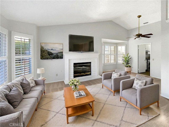 living room with light hardwood / wood-style flooring, lofted ceiling, a fireplace, and plenty of natural light